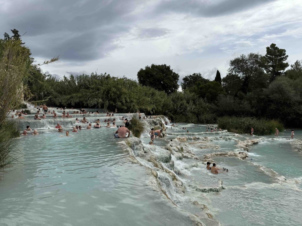 View of Saturnia Hot Springs with many people enjoying the water